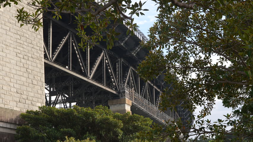 Close up of the steel structure and sandstone pylon of the Sydney Harbour Bridge framed by leafy trees. Sydney, New South Wales, Australia.