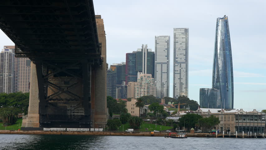 Sydney city towers rise beyond the southern end of the Sydney Harbour Bridge, combining historic bridge architecture with the modern skyline. Sydney, New South Wales, Australia.