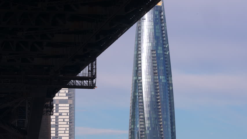Modern glass high-rise viewed beside the dark steel underside of the Sydney Harbour Bridge. Sydney, New South Wales, Australia.
