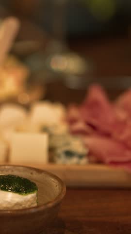 Close-up of fresh goat cheese with herb pesto beside an antipasto platter in Piedmont, Italy.