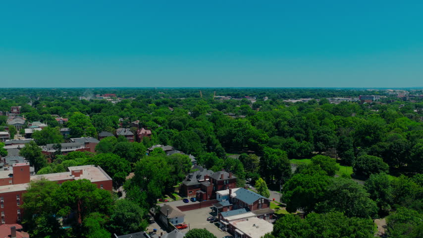 Beautiful drone shot highlighting urban forestry, where a dense canopy of mature green trees integrates perfectly with residential and commercial city infrastructure. Louisville, Kentucky