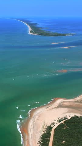Aerial view of the coastal landscape at Cape Hatteras National Seashore in North Carolina, USA, showing a long sand spit, forested coastline and turquoise waters