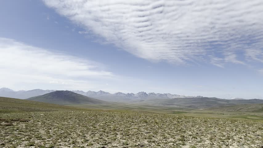 Open Deosai plains extend toward distant mountain ranges beneath patterned clouds, Gilgit-Baltistan, Pakistan