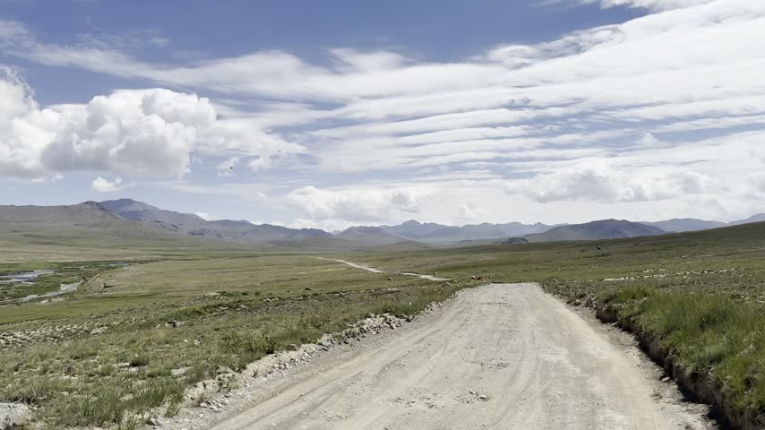 Unpaved road crosses the open Deosai plateau beneath layered clouds, Gilgit-Baltistan, Pakistan