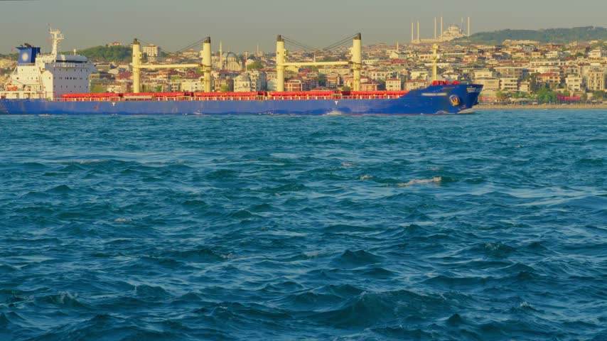 Large Blue Cargo Ship Sailing in the Bosphorus Strait with Istanbul Skyline and Mosque in Background