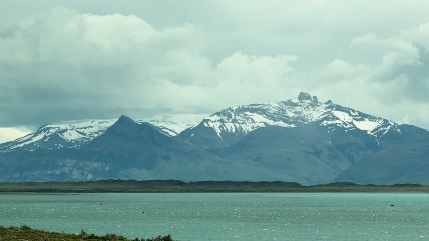 Vast, spectacular landscape of Lago Argentino in Patagonia, Argentina. The Andes mountain range with snowy peaks reflects on the water