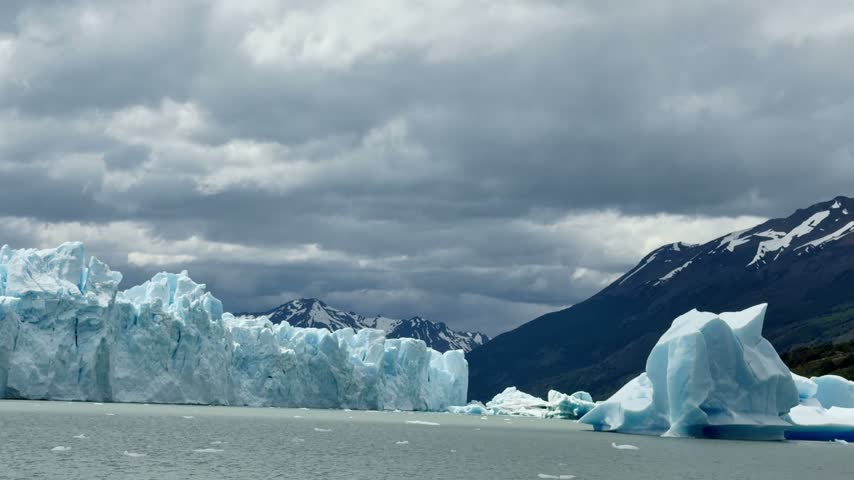 Immense Perito Moreno Glacier front advancing into Lake Argentino. Patagonian landscape showcases icebergs and snowy mountains
