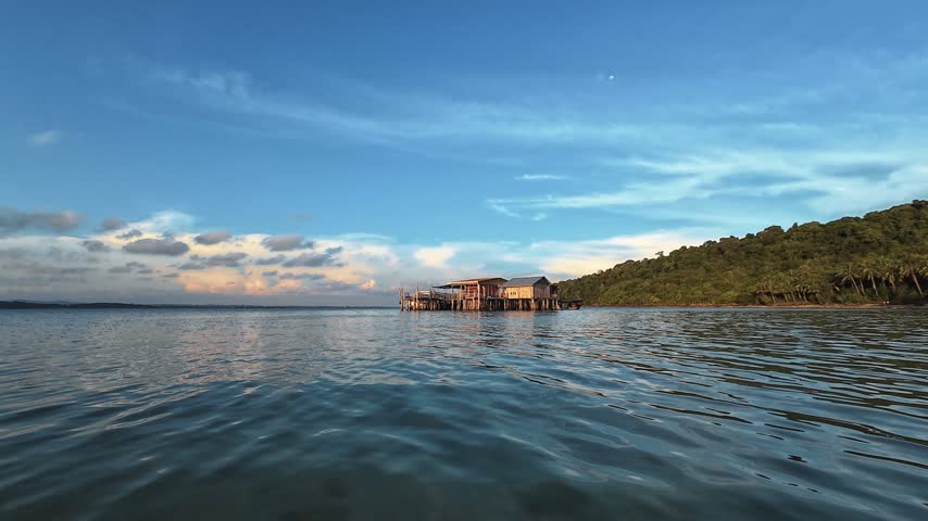 Floating waterfront restaurant structure beside a calm tropical bay