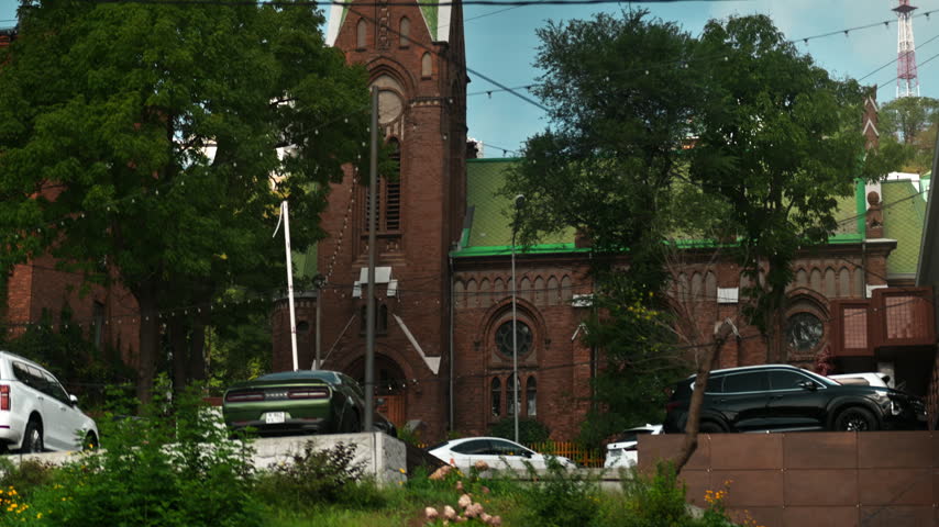 A red-brick Gothic church with a green roof stands in the middle of the city. Religion and culture.