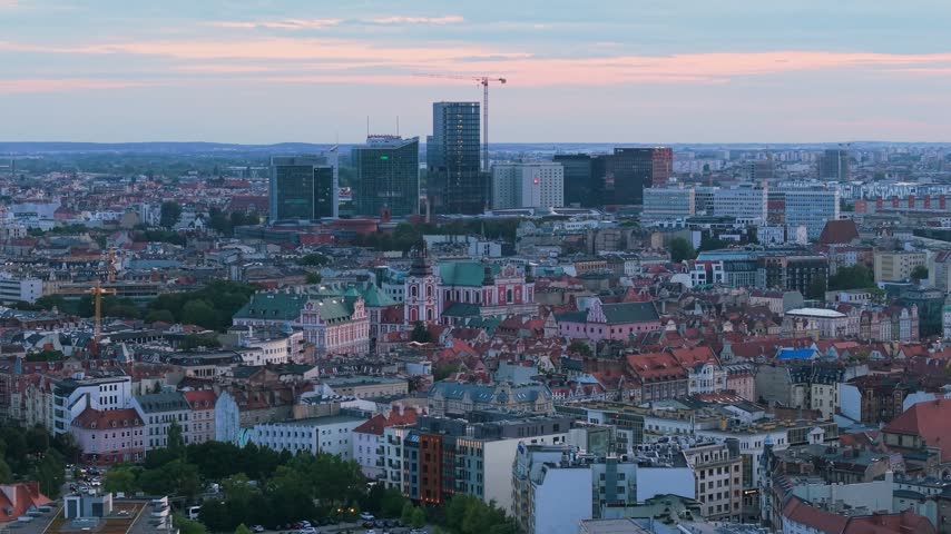 Stunning aerial panorama of Poznan, Poland, capturing the transition from day to night over the historic old town, with the beautiful Poznan Fara church, and the modern financial district skyline