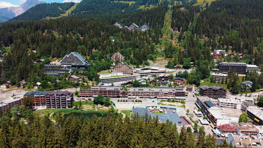 Cars move along roads below as the drone advances into Crans-Montana