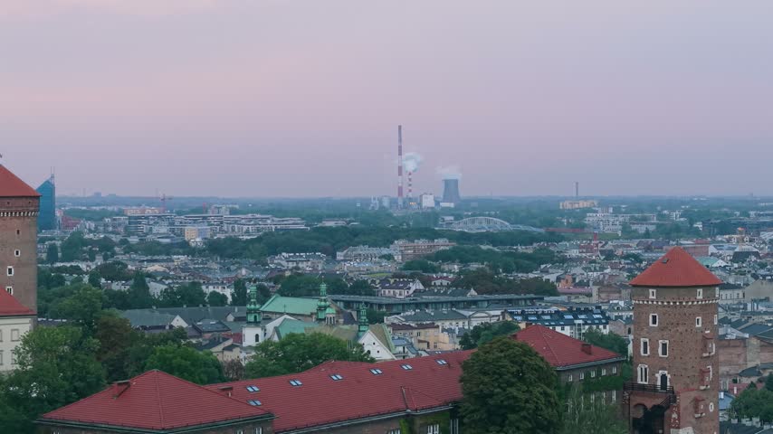 Stunning panoramic view of Krakow, Poland, from a high angle, showing the historic Old Town with its red rooftops and the iconic Wawel Castle against a dramatic sky at twilight