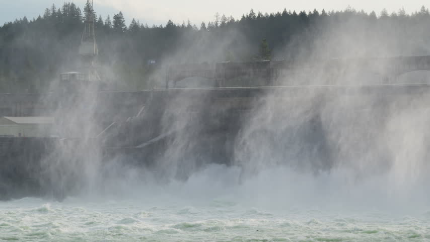 Turbulent water surging through Bonneville Dam on the Columbia River in Oregon, creating towering spray and mist around the hydroelectric facility.