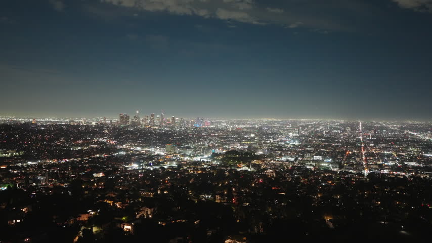 Glowing lights surround the Los Angeles skyline after dark, revealing an expansive urban landscape filled with illuminated streets, distant skyscrapers and vibrant Southern California night scenery.