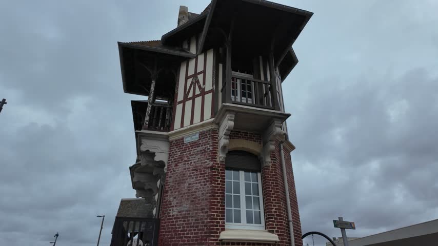 Historic seaside house in Mers-les-Bains featuring red brick walls, half-timbered upper levels, projecting balconies, wide roof eaves and decorative details