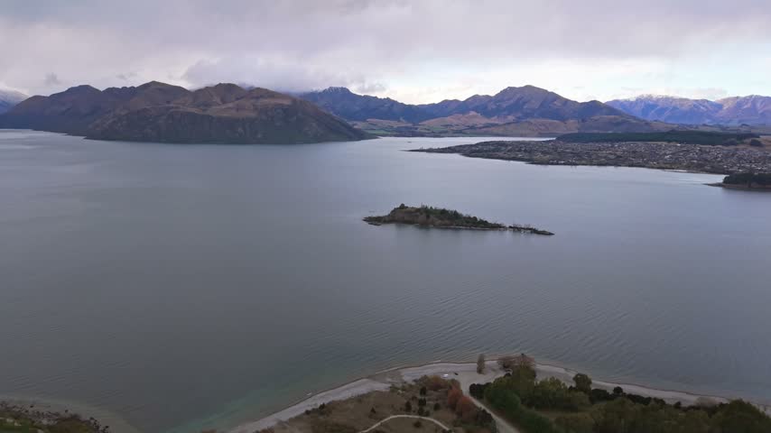Aerial view approaching Ruby Island on Lake Wanaka with mountains and shoreline visible