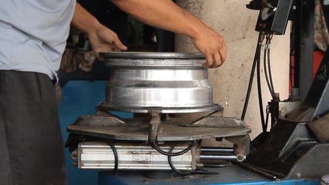 Technician remove tubeless valve of wheel rim in automobile shop (Full High Definition)