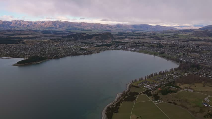 Aerial view over Lake Wanaka, Ruby Island, and Wanaka township with mountains beyond