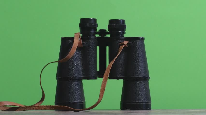 takes classic binoculars from the table. Close-up on a green background