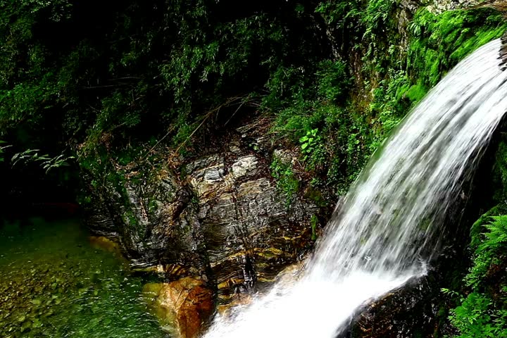 Scenic time lapse footage of a beautiful waterfall flowing through green tropical rocks