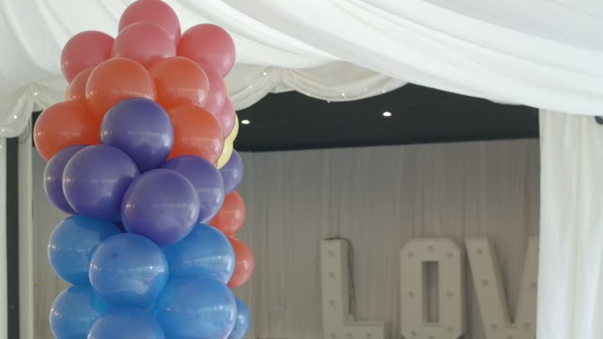 Colorful balloon column beside LOVE letters at an elegant indoor celebration.