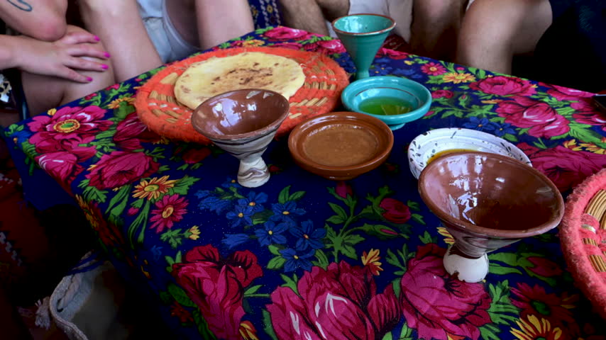 Marrakech, morocco. August 9, 2026. Colorful table set with a traditional moroccan meal. A group of people enjoying fresh bread with argan oil and amlou on a floral tablecloth