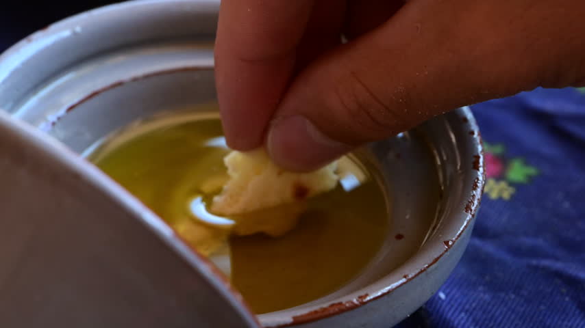 Marrakech, morocco. August 9, 2026. Slow motion close up of a person dipping a piece of fresh moroccan bread into a bowl of extra virgin olive oil. Traditional appetizer
