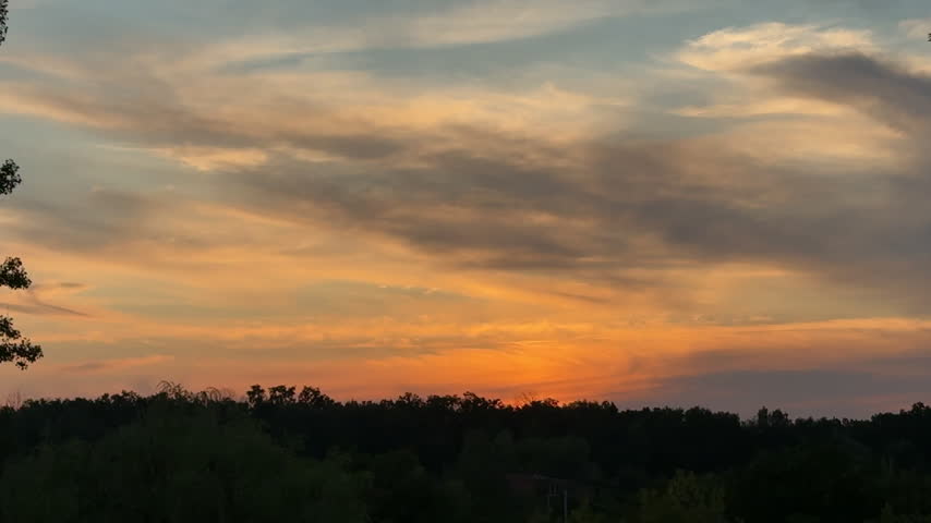 Scenic Golden Hour Sunset Over Dark Forest Silhouette with Vibrant Orange and Yellow Clouds