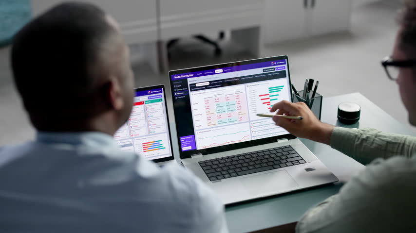 Data Analyst And Manager Review AI Model Risk On Laptop For Compliance.