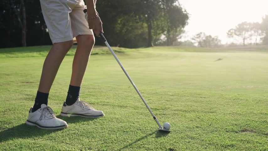 Close up view of a golf player hitting the ball with an iron club. The professional golfer is playing on a beautiful, sunny day