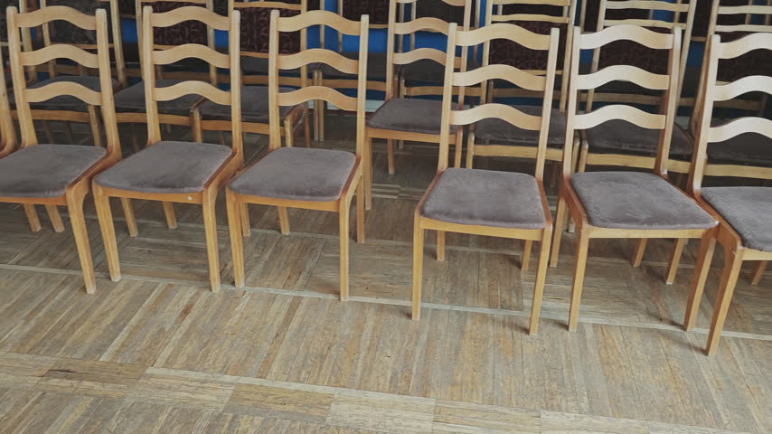 Rows of empty wooden chairs standing in an empty auditorium hall ready for a concert, lecture, or conference event