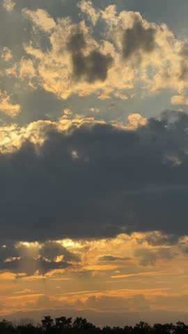 Vertical Dramatic Sunset Sky with Sun Rays Breaking Through Dark Clouds Over Forest