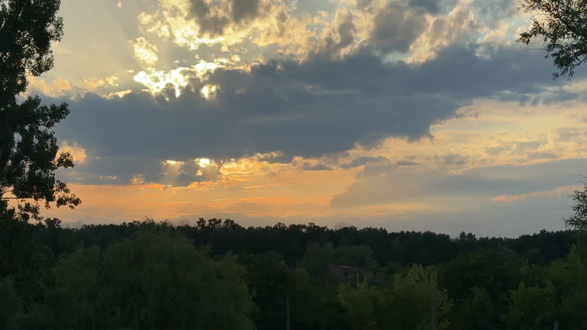 Dramatic Sunset Sky with Sun Rays Breaking Through Clouds Over Forest