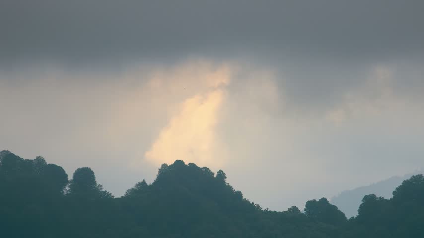 Dramatic Clouds Over Forested Hills at Sunset