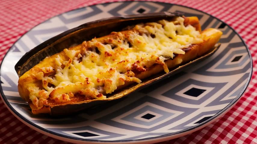 Close-Up Zoom of a Baked Stuffed Plantain Canoe with Melted Cheese