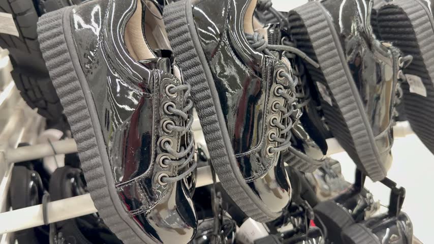 Display of black patent leather platform shoes in a store. Casual modern footwear, retail fashion shop display, shiny shoes texture.