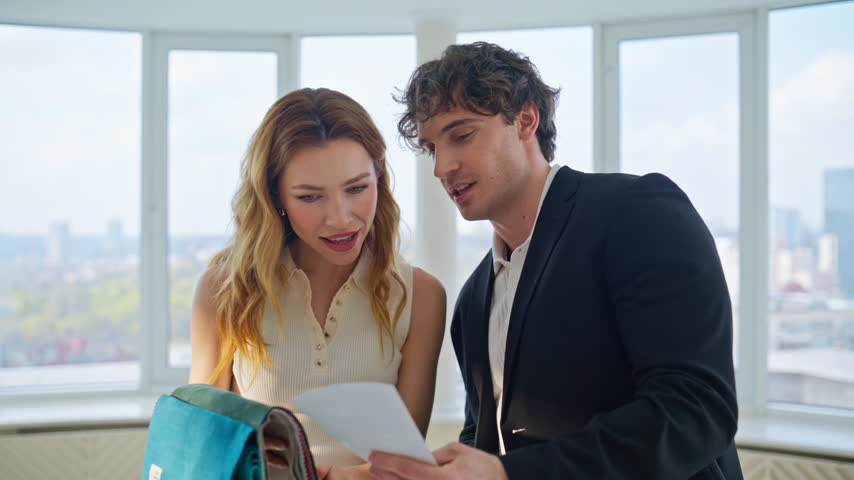 Two people selecting fabric swatches modern office. Interior designer showing color samples to happy woman, textile consultation meeting bright panoramic room. Design project collaboration idea.