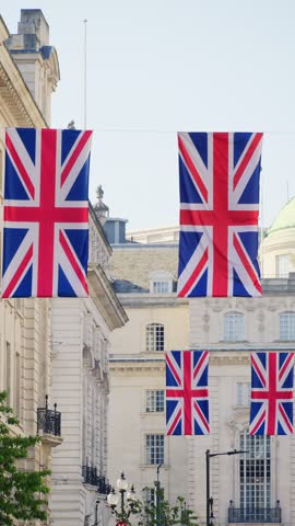 British flags hanging on wires against historic architecture in London city center during sunny day.