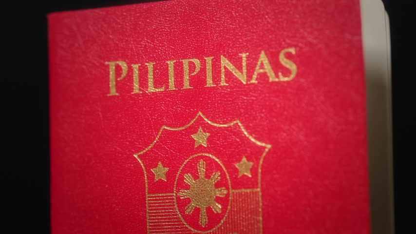 Extreme close up of a Philippine passport showing golden coat of arms and text on a red cover.
