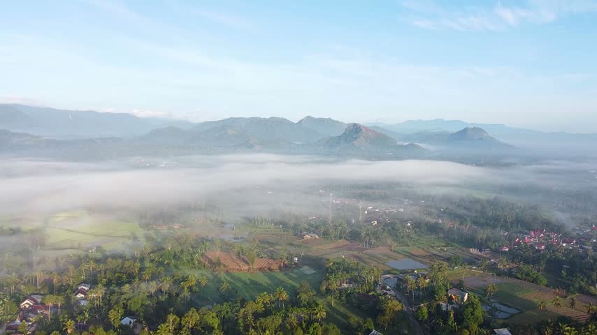 Aerial view of misty valley with village and fields