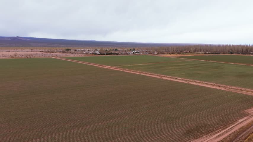 Wide aerial view of cultivated farmland and rural landscape under cloudy sky