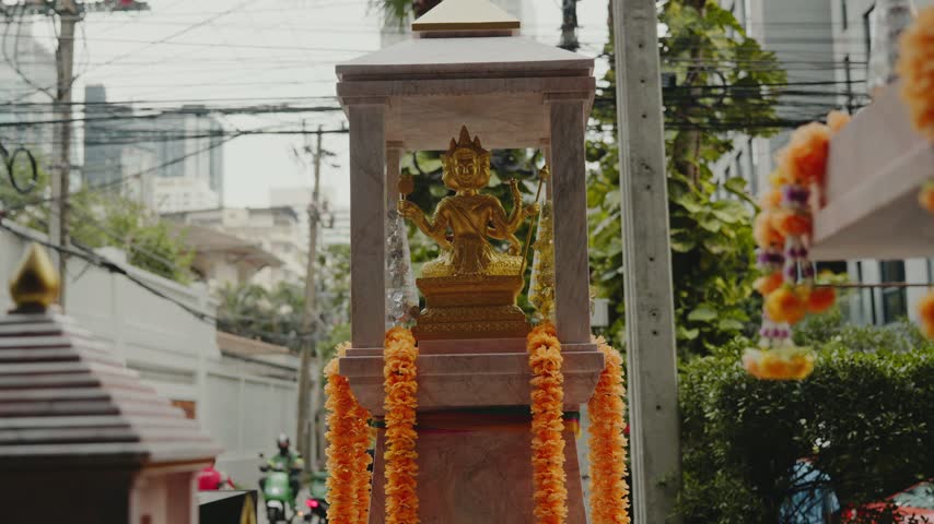 Golden four faced brahma statue in a spirit house on a street in bangkok, thailand