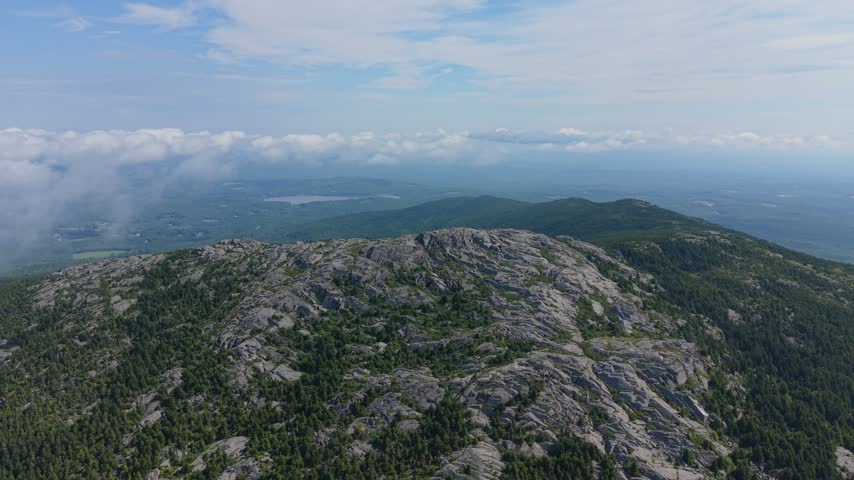Aerial view of rocky summit and green forested slopes of Mount Monadnock on a sunny day in New Hampshire