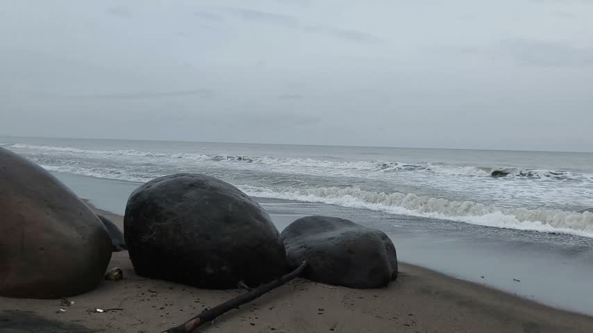 Aceh, Indonesia-09.20.2026:
Ocean Waves Crashing on Sandy Beach with Large Boulders.