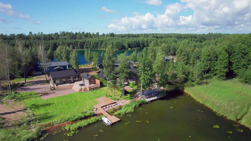 An Aerial Glide Passes Private Holiday Apartments, Wooden Decks and a Jetty Among Trees and Reeds Beside the Porvoo River Estuary in Finland.