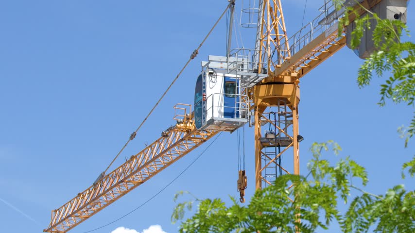 Close-up of a yellow construction tower crane cabin against clear blue sky in Cassis, France.