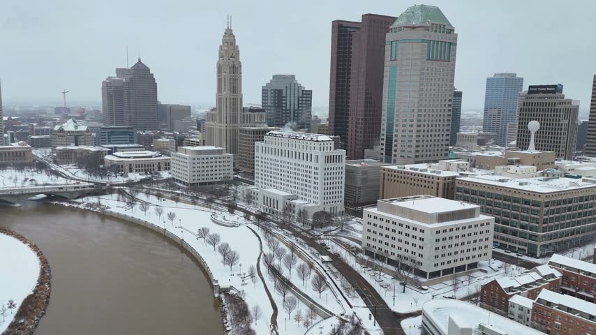 4K Aerial drone shot of Columbus Ohio skyline in winter covered with fresh snow, captured , showcasing the downtown cityscape, high-rise buildings, urban architecture, and snowy winter landscape.
