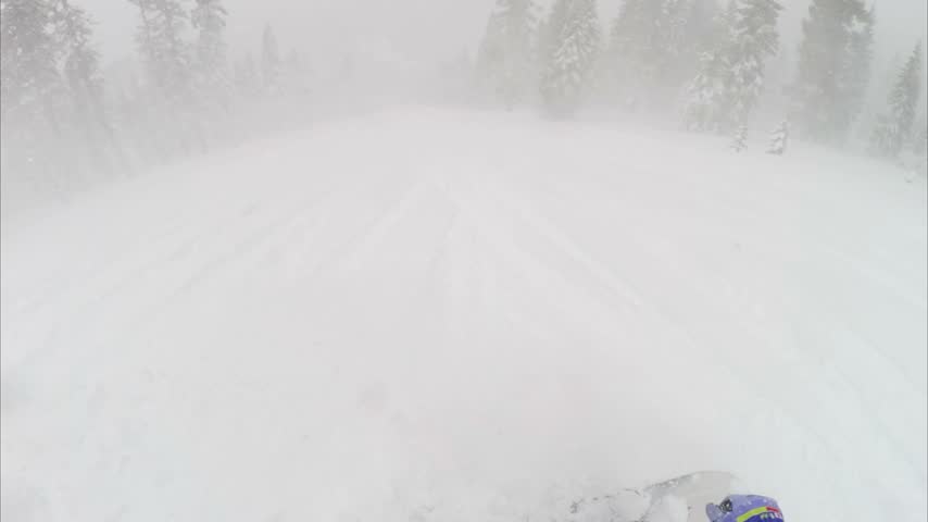 Snowboarder riding through heavy snow at Northstar California ski resort in Lake Tahoe, surrounded by snow-covered mountain terrain and winter forest.
