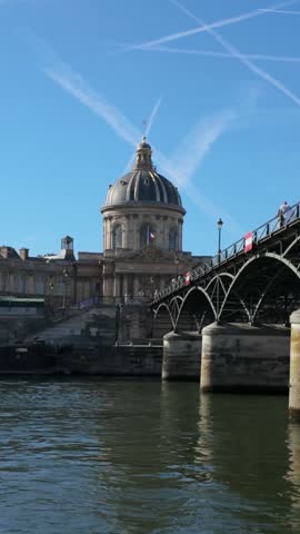 The domed Institut de France building rises beyond Pont des Arts above the Seine river in Paris, France.