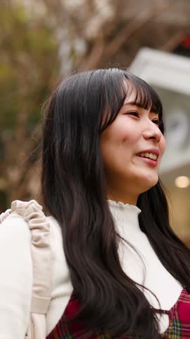 Close-up of a happy woman with long dark hair smiling and looking upward in Tokyo.